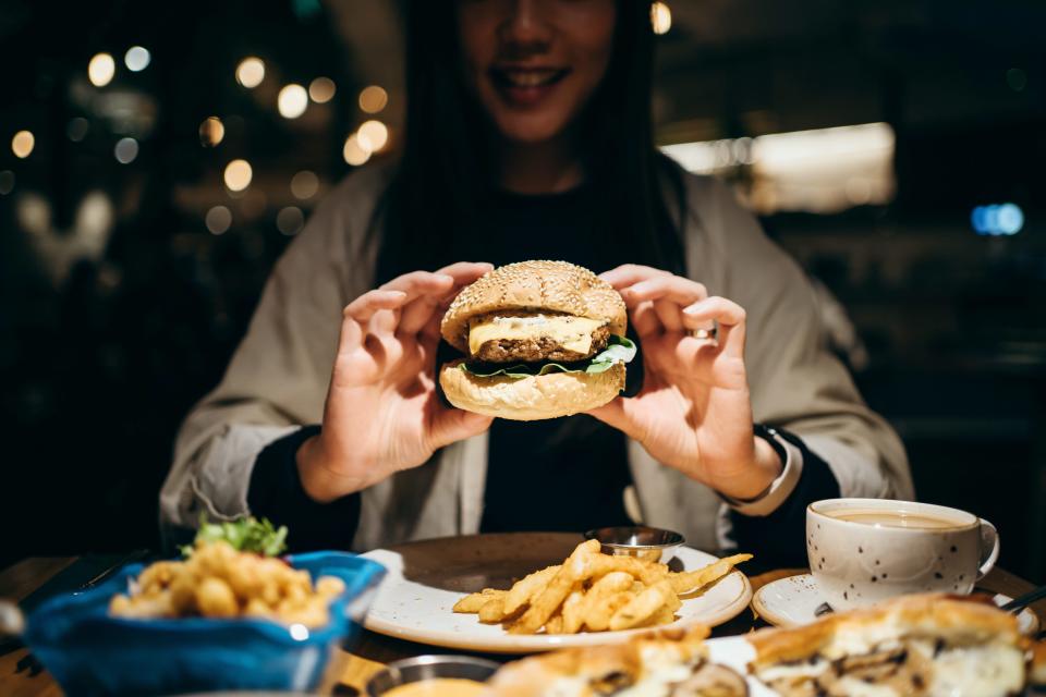 A woman eating a burger and chips.