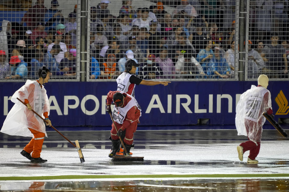 Marshals clear the track of surface water after rain delays the start of the Singapore Formula One Grand Prix, at the Marina Bay City Circuit in Singapore, Sunday, Oct. 2, 2022. (AP Photo/Vincent Thian)