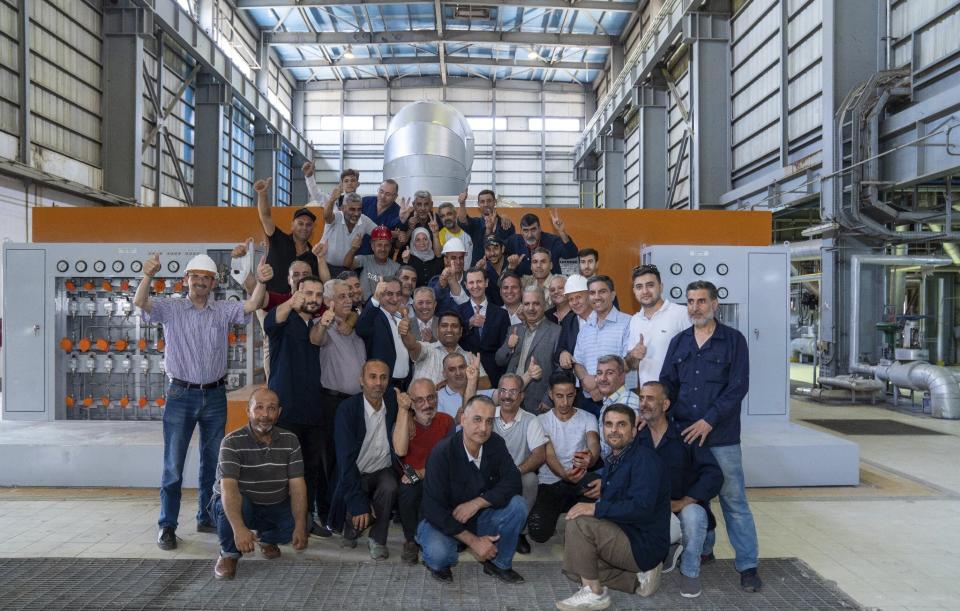 In this photo released on the official Facebook page of Syrian Presidency, Syrian President Bashar Assad, centre, poses for a photograph during his visits to a power station in the eastern part of Aleppo province, Syria, Friday, July 8, 2022. Assad made a rare visit to the northern province of Aleppo on Friday to inaugurate a power station that was once held by insurgents and suffered wide damages during the war, state media reported. (Syrian Presidency Facebook page via AP)