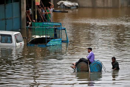 A man uses a makeshift raft to move out of a flooded neighbourhood after heavy rains in Ahmedabad, July 27, 2017. REUTERS/Amit Dave