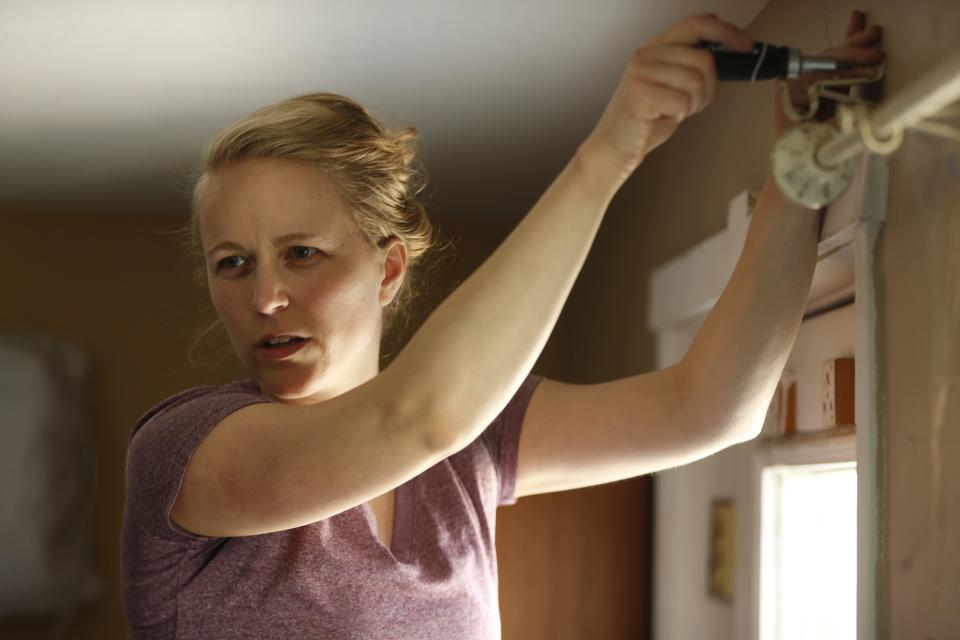 ICU nurse Lydia Corriveau, 32, installs curtain rods where she will live with fellow ICU nurse Jason Odhner, 43, at their temporary home in Phoenix, Ariz. on March 19, 2020. The two are quarantining together to protect their families as they are at higher risk.