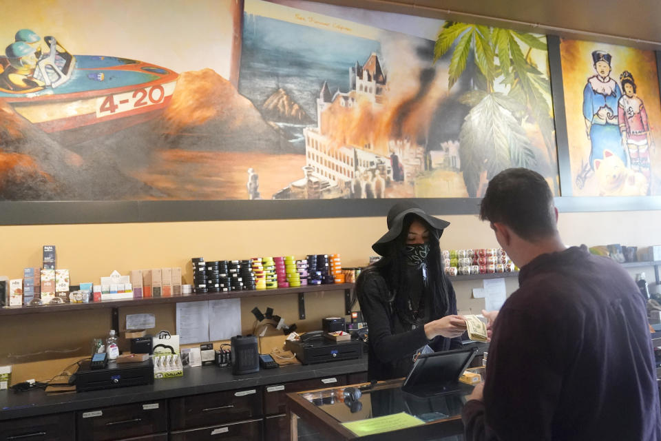 Budtender Cee Jenkins, second from right, rings up a customer at a California Street Cannabis Company location in San Francisco on March 20, 2023. Along the West Coast, which has dominated U.S. marijuana production from long before legalization, producers are struggling with what many call the failed economics of legal pot...a challenge inherent in regulating a product that remains illegal under federal law. (AP Photo/Jeff Chiu)