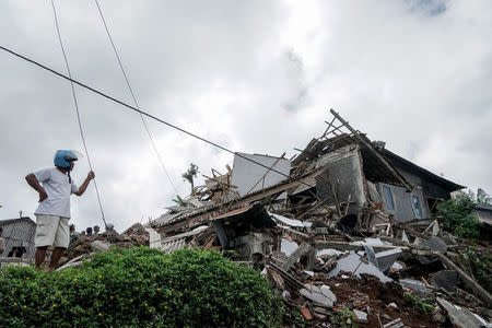 A man stands near a collapsed home following yesterday's 4.4 magnitude quake in Kertosari Village, Banjarnegara, Central Java, Indonesia April 19, 2018 in this photo taken by Antara Foto. Antara Foto/Idhad Zakaria / via REUTERS