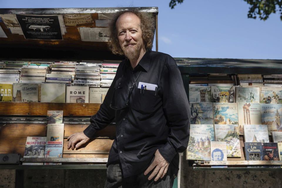 Jerome Callais head of the Paris Booksellers' Cultural Association, poses at his bookseller booth along the Seine Riverbank in Paris, Tuesday, Aug. 22, 2023. The host city of Paris vowed to deliver an extraordinary grand opening on July 26, 2024, as the ceremony is expected to draw about 600,000 spectators to the Parisian quayside. Citing security measures, the Paris police prefecture ordered on July 25 the removal of 570 stationary boxes out of which booksellers have operated for decades on the quays of the Seine river. (AP Photo/Sophie Garcia)