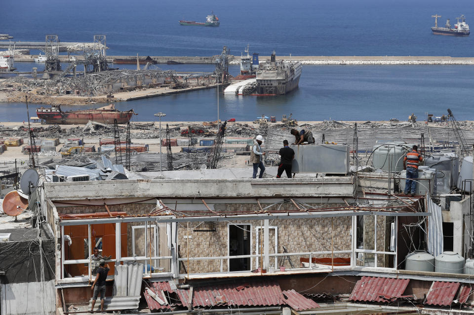 Workers repair water tanks and damaged apartments overlooking the site of the Aug. 4 explosion that hit the seaport, in Beirut, Lebanon, Thursday, Aug. 27, 2020. (AP Photo/Hussein Malla)