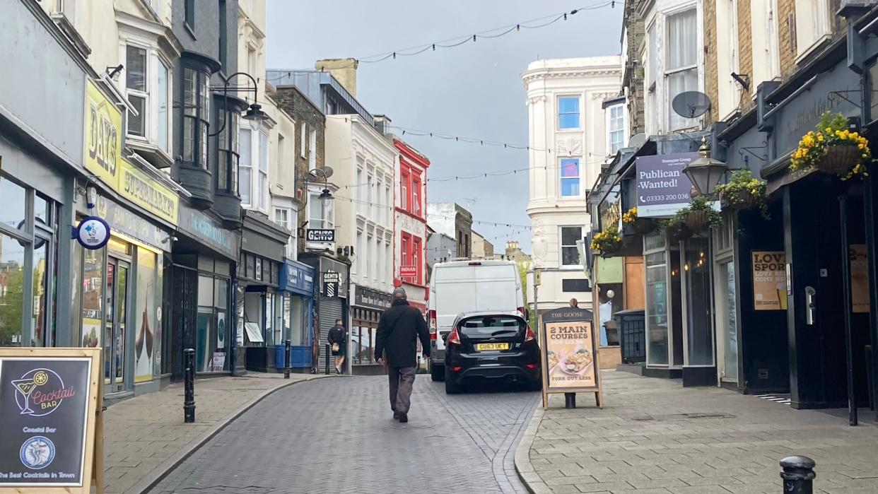 A brick high street with shops flanking either side of the street 