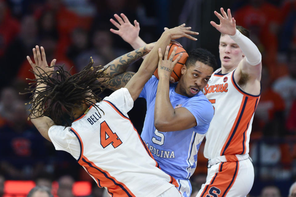 North Carolina forward/center Armando Bacot, center, fights for a rebound against Syracuse forward Chris Bell, left, and guard Justin Taylor during the first half of an NCAA college basketball game in Syracuse, N.Y., Tuesday, Feb. 13, 2024. (AP Photo/Adrian Kraus)