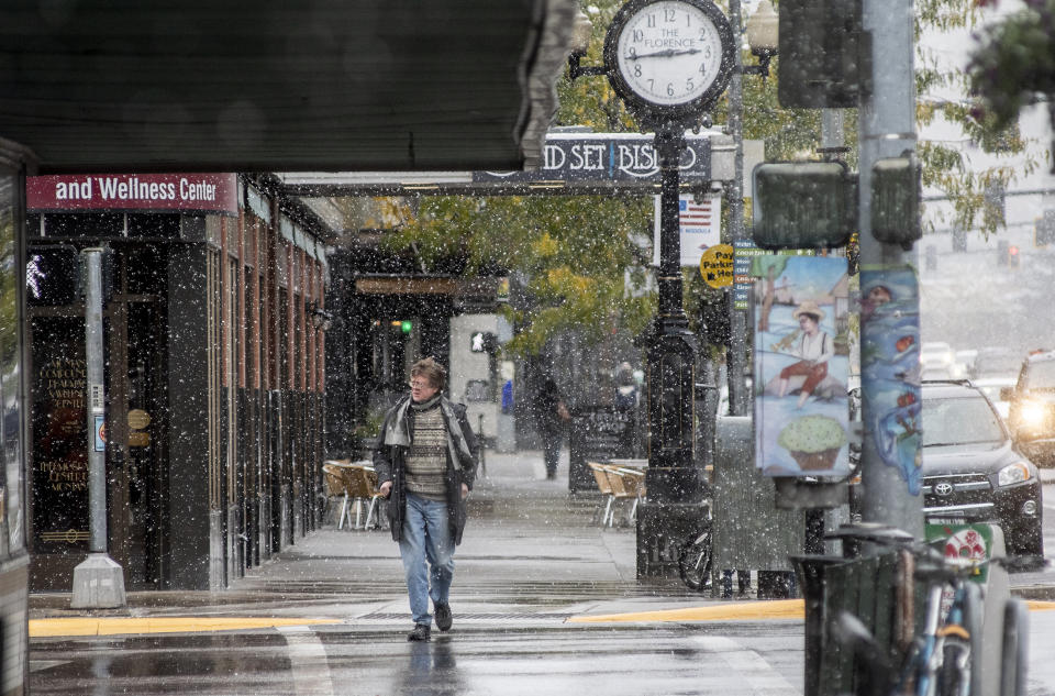 FILE - In this Sept. 29, 2019 file photo, a pedestrian crosses Front Street under snowfall in Missoula, Mont. Under a new proposal, a metro area would have to have at least 100,000 people to count as an MSA, double the 50,000-person threshold that has been in place for the past 70 years. Cities formerly designated as metros with core populations between 50,000 and 100,000 people would be changed to “micropolitan" statistical areas instead. (Ben Allan Smith/The Missoulian via AP)