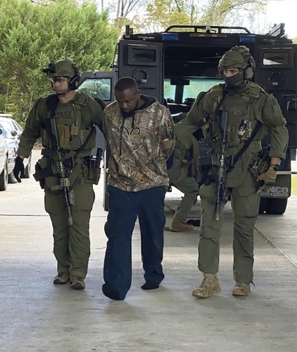 In this photo released by Georgia Department of Public Safety, Damien Ferguson, center, is taken into custody by officers of a state SWAT team and a division of the U.S. Marshals Service, Sunday, Oct. 10, 2021, in Alamo, Ga. Ferguson is accused of gunning down a Georgia police officer during his first shift with the department Saturday, Oct. 9. Authorities said the ambush was in retaliation for the officer's arrest of an associate of Ferguson's hours earlier. (Georgia Department of Public Safety via AP)