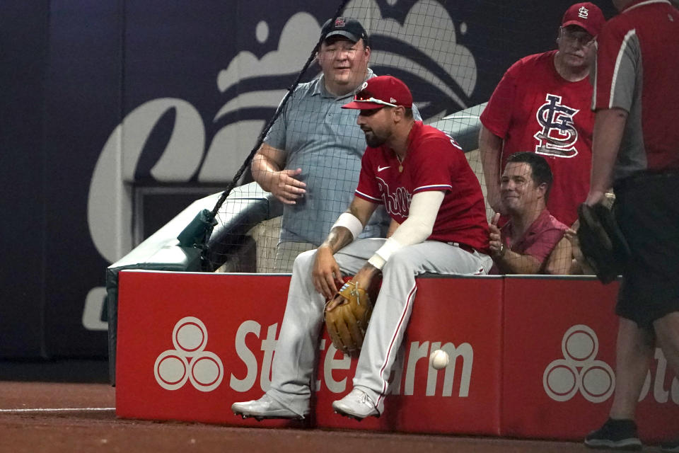 Philadelphia Phillies right fielder Nick Castellanos sits on the wall after he was unable to catch a foul ball by St. Louis Cardinals' Paul Goldschmidt during the eighth inning of a baseball game Monday, July 11, 2022, in St. Louis. (AP Photo/Jeff Roberson)