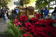 Visitors look at a replica of the U.S. Supreme Court adorned with different varieties of poinsettias on display at the Smithsonian's U.S. Botanical Garden, Saturday, Dec. 16, 2023, in Washington. (AP Photo/Manuel Balce Ceneta)