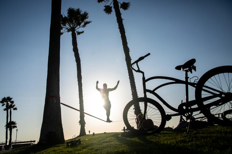 Damien Arredondo walks the slack line in Noble Park at the Strand in Hermosa Beach.