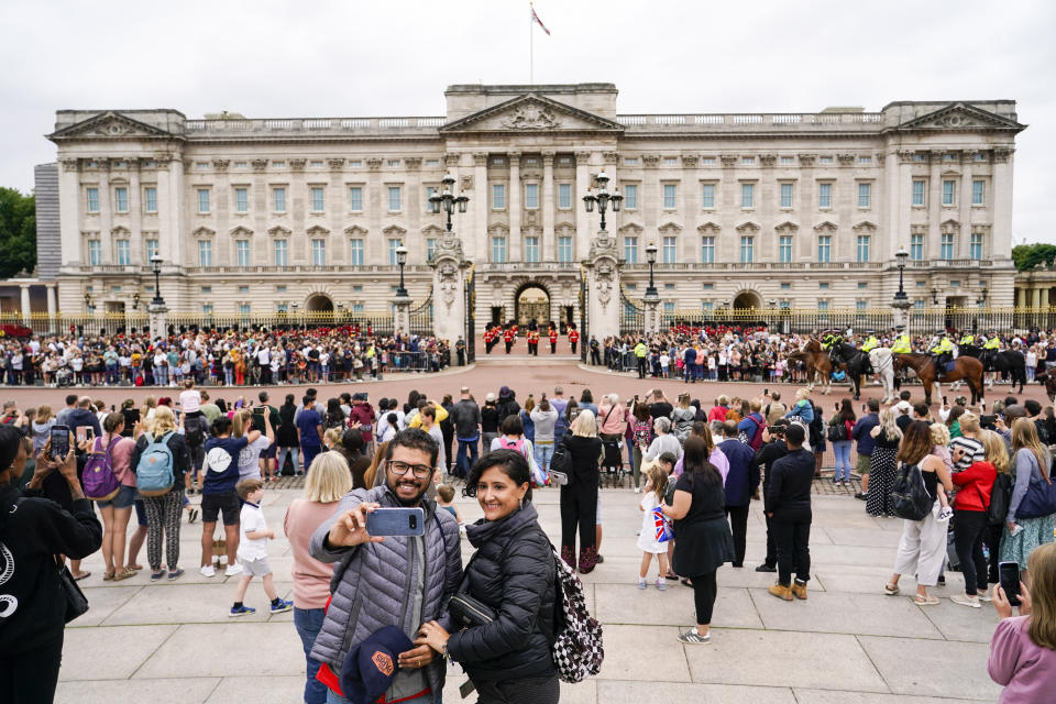 FILE - Members of the public watch the Changing of the Guard ceremony at Buckingham Palace, London, Aug. 23, 2021, which is taking place for the first time since the start of the coronavirus pandemic. As countries across Europe reimpose lockdowns in response to surging COVID-19 cases and deaths, the UK – long one of Europe’s hardest-hit countries -- carries on with a policy of keeping everything as normal as possible. (AP Photo/Alberto Pezzali, File)