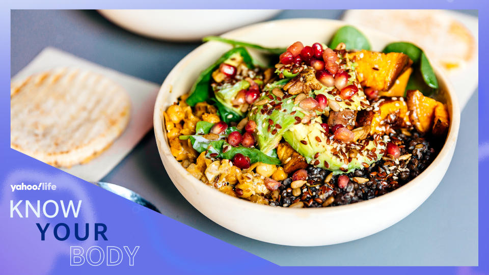 A bowl of lentils and tofu sprinkled with pomegranate seeds with lettuce and vegetables.