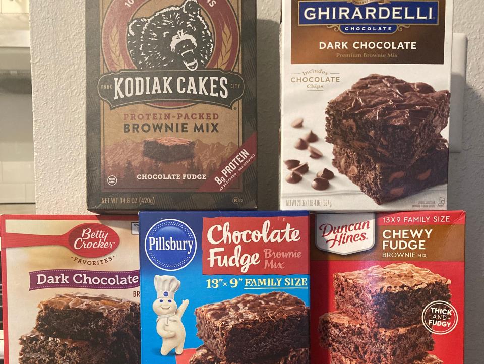 Boxes of five brownie mixes arranged in a pyramid. On top, from left to right Kodiak Cakes and Ghirardelli mixes stand and on the bottom from left to right, Betty Crocker, Pillsbury, and Duncan Hines mixes are arranged.