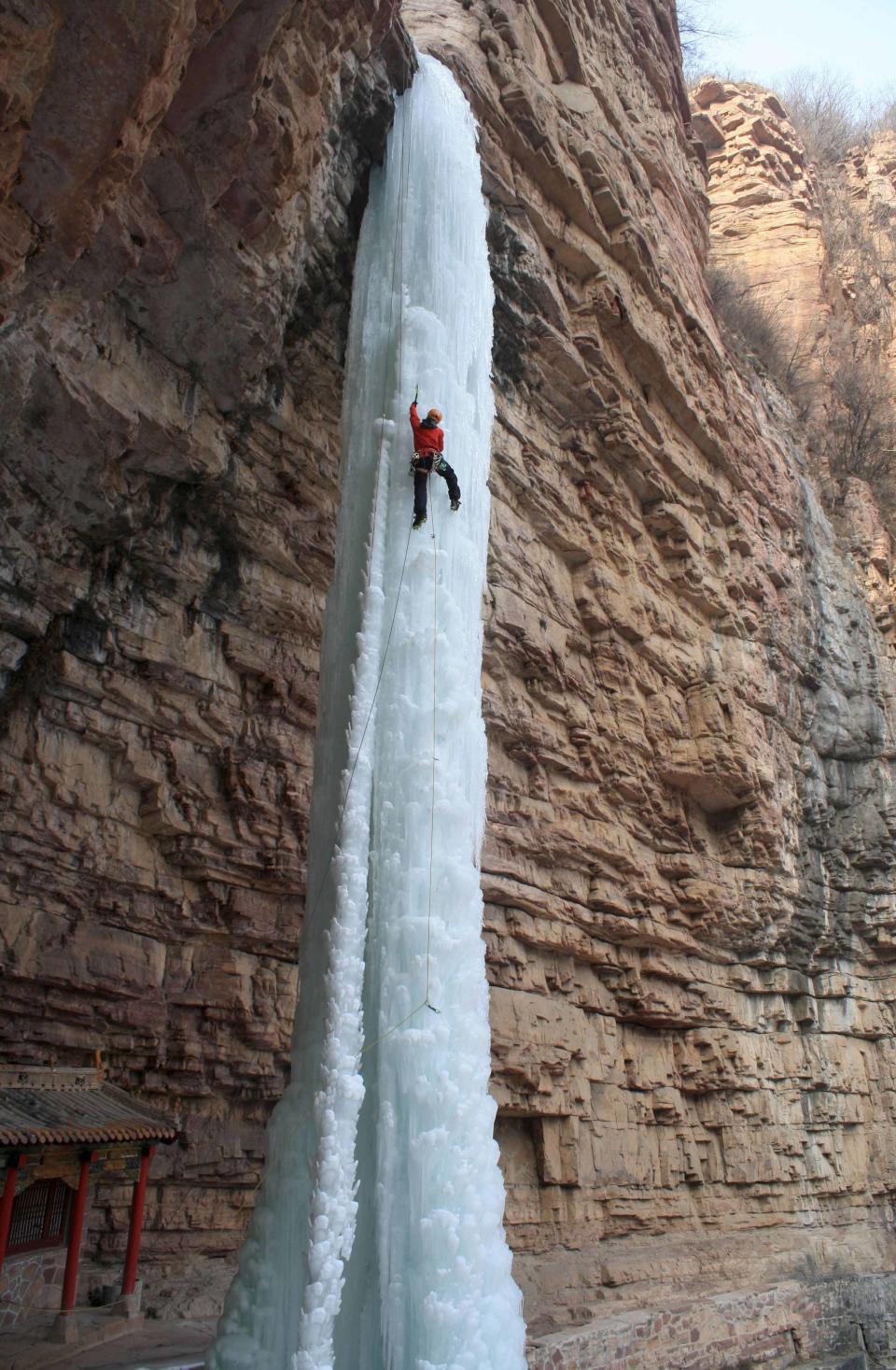 A man climbs a frozen waterfall, which stands almost 50m high, in Zhangshi Rock Park, northern China’s Hebei Province.