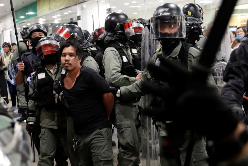 Riot police members carry a detained protester, at a shopping mall in Tai Po in Hong Kong