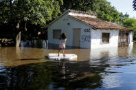 <p>Ein junges Mädchen bewegt sich auf einem Floß aus Styropor durch ein überschwemmtes Gebiet am Rande von Paraguays Hauptstadt Asunción. Nach heftigen Regenfällen war der Río Paraguay über die Ufer getreten. (Bild: Reuters) </p>