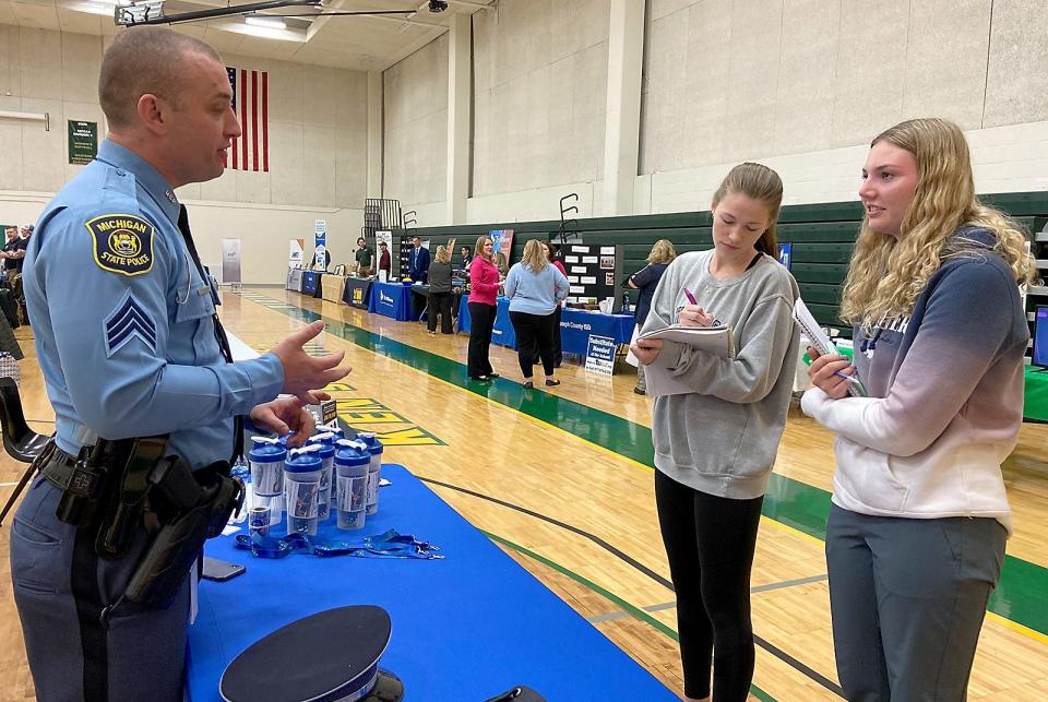 Alexis Clemens and Kailey Orton speak with Sgt. Alan Oosterbaan of Michigan State Police Wednesday at a job fair at Glen Oaks Community College.