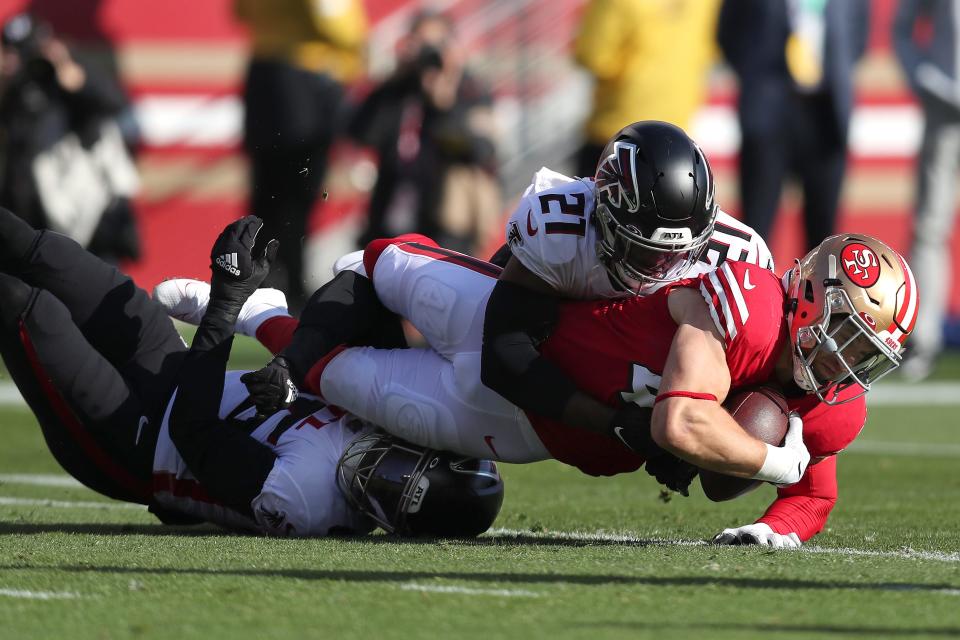 San Francisco 49ers fullback Kyle Juszczyk, right, is tackled by Atlanta Falcons inside linebacker Deion Jones, bottom, and safety Duron Harmon (21) during the first half of an NFL football game in Santa Clara, Calif., Sunday, Dec. 19, 2021. (AP Photo/Jed Jacobsohn)