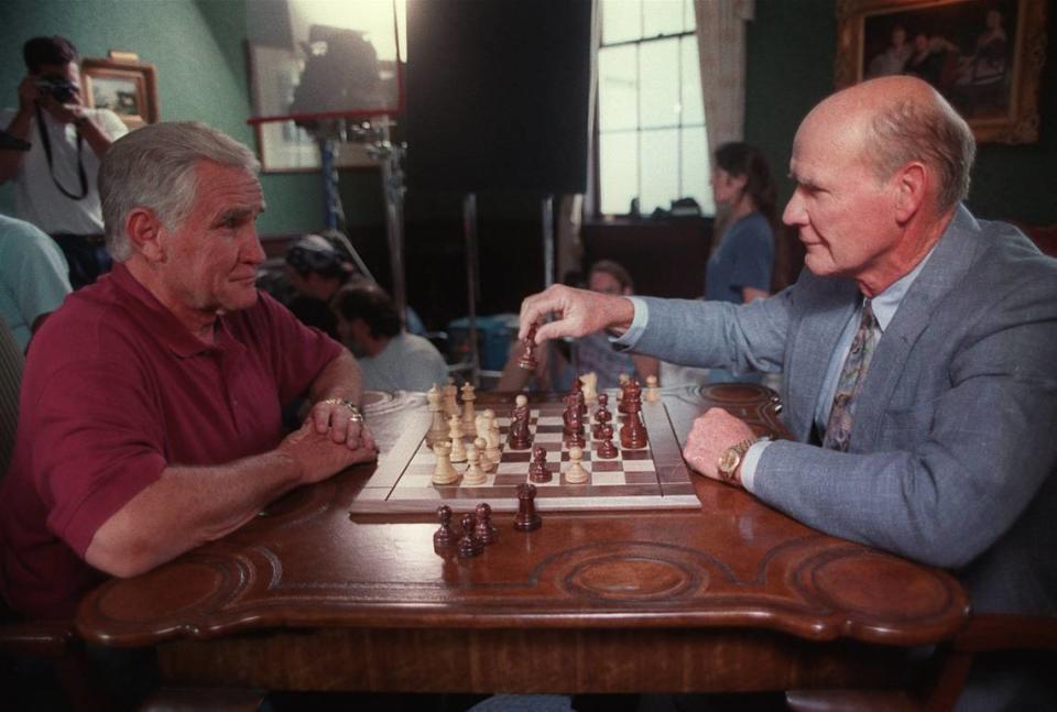 Former Miami Dolphins coach Don Shula (left) watches former Dallas Cowboys coach Tom Landry make a chess move on July 19, 1996, at Myers Park Country Club during the filming of a promotion for an NFL Films show called “Head Coach.” Shula, 90, died Monday.