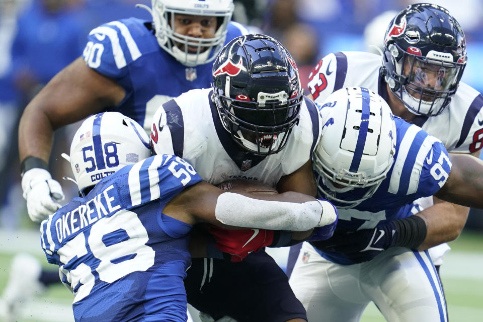 Houston Texans' Mark Ingram (2) is tackled by Indianapolis Colts' Bobby Okereke (58) and Al-Quadin Muhammad (97) during the second half of an NFL football game, Sunday, Oct. 17, 2021, in Indianapolis. (AP Photo/Michael Conroy)