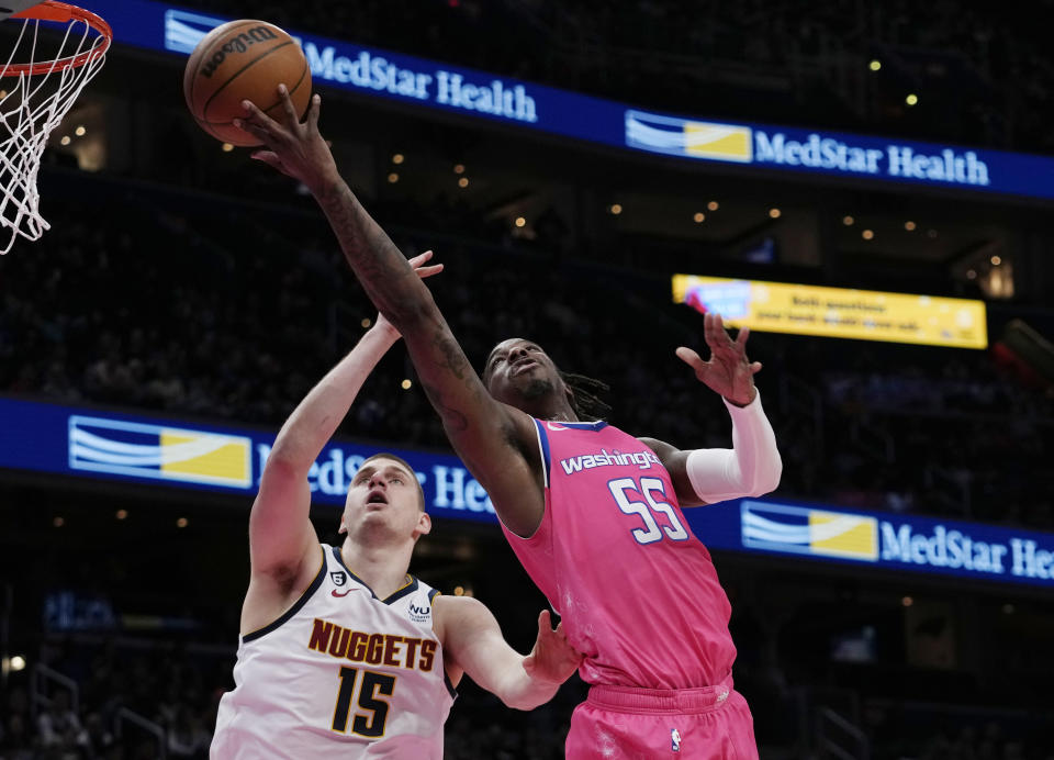 Washington Wizards guard Delon Wright (55) goes up to over Denver Nuggets center Nikola Jokic (15) during the first half of an NBA basketball game Wednesday, March 22, 2023, in Washington. (AP Photo/Carolyn Kaster)