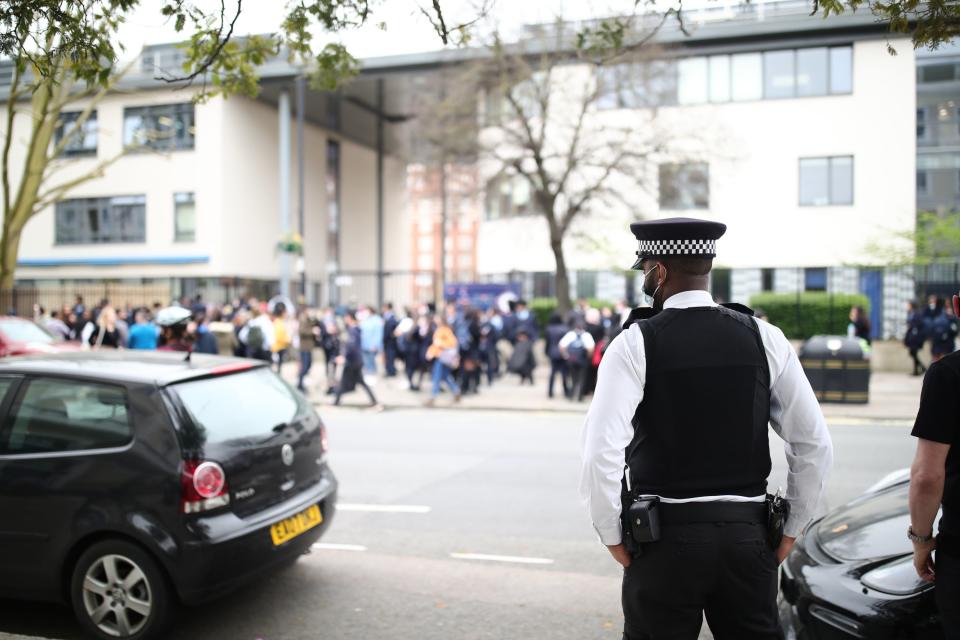 <p>A police officer outside Pimlico School where pupils protested against Mr Smith’s uniform policies</p> (PA)