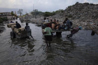 Residents wade through a street that was flooded after a rainfall, in the Cite Soleil shanty town of Port-au-Prince, Haiti, Friday, Oct. 1, 2021. Currently, the country is still spinning from the July 7 killing of President Jovenel Moise and a 7.2 magnitude earthquake that killed more than 2,200 people in August. (AP Photo/Rodrigo Abd)