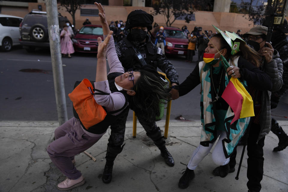 A police officer tries to prevent an anti-government protester from pulling the hair of a woman who is part of group that appeared to show their support for the government during a march of healthcare workers critical of the government, in La Paz, Bolivia, on July 21, 2022. (AP Photo/Juan Karita)