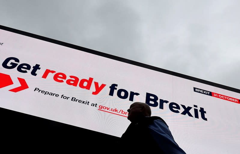 FILE PHOTO: A man passes an electronic billboard displaying a British government Brexit information awareness campaign advertisement in London, Britain