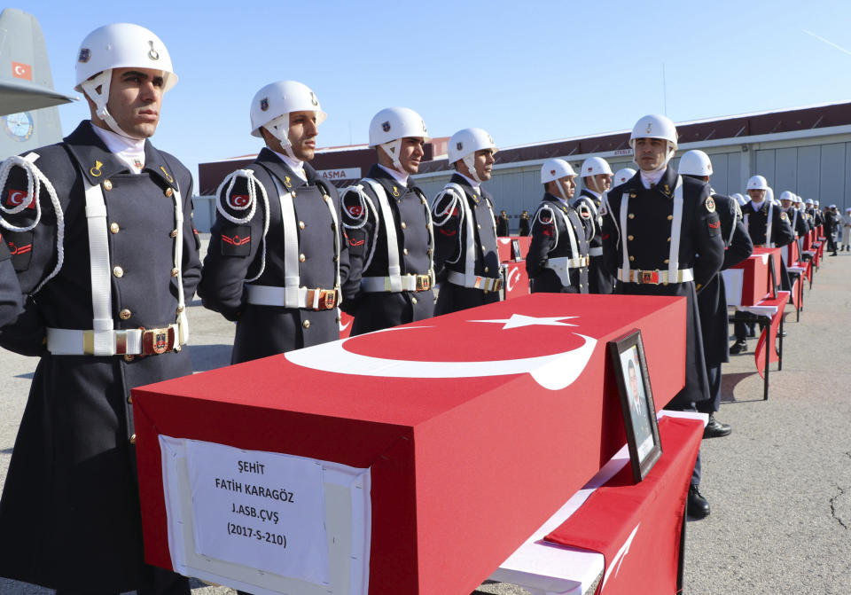 Honour guards stand at the coffins of 12 soldiers who lost their lives while trying to rescue people from under snow after two deadly avalanches, in Van, Turkey, Thursday, Feb. 6, 2020. Turkish news agencies reported that search efforts have resumed in eastern Turkey, following two avalanches that killed dozens and left at least one person missing. (DHA via AP)