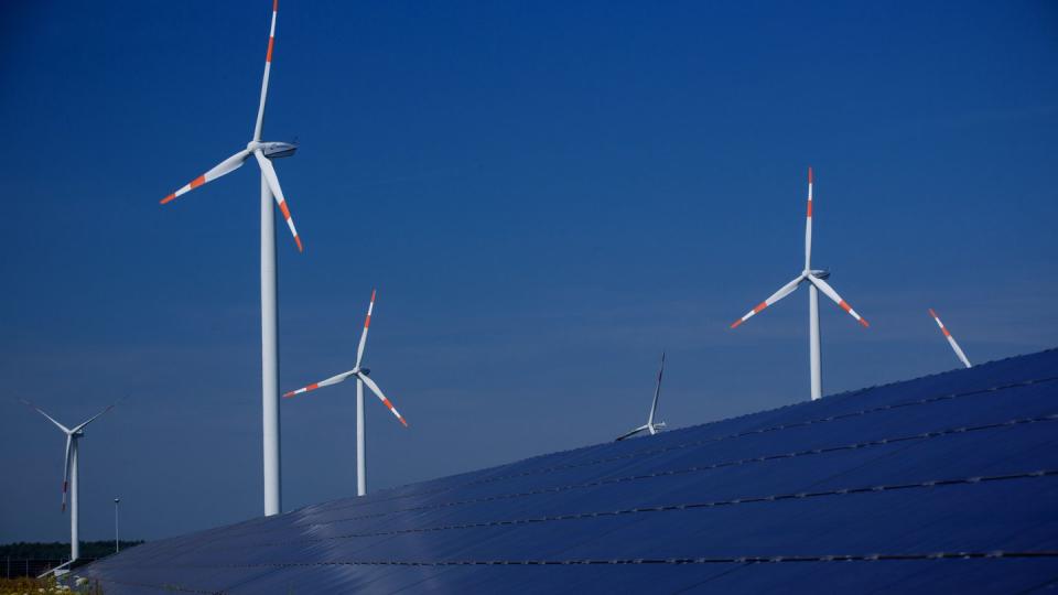 Windräder zur Stromerzeugung drehen sich am hinter einem Solarpark. Der Ökostrom-Anteil soll weiter steigen.