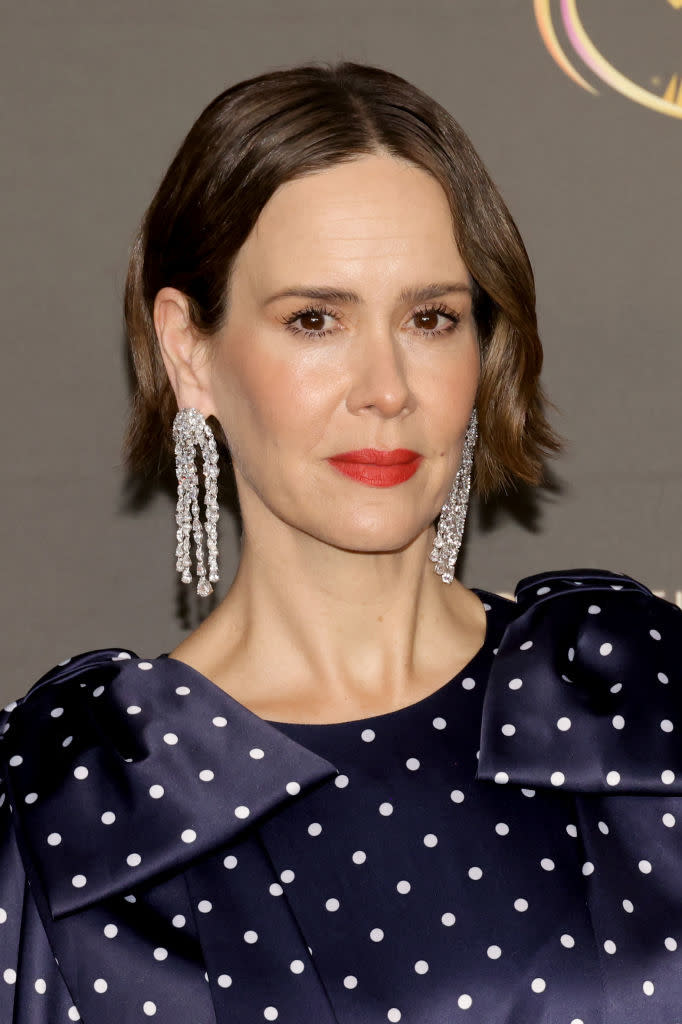 Sarah Paulson wearing a polka-dot dress with large, sparkly chandelier earrings, attending an event