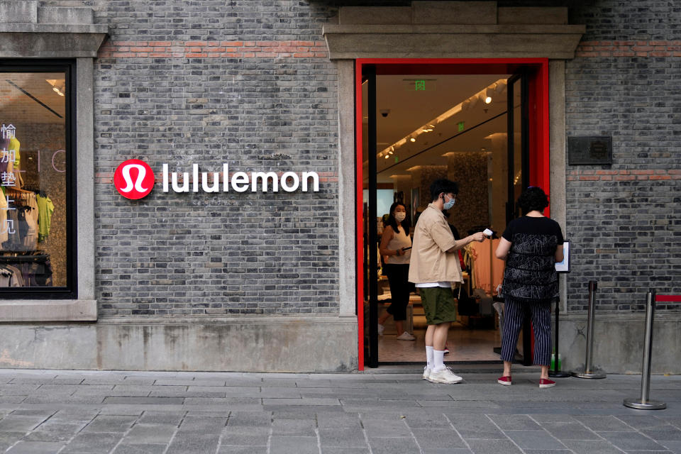 A staff member holds a thermometer to measure the temperature of a customer at an entrance to a Lululemon store, following the coronavirus disease (COVID-19) outbreak in Shanghai, China June 21, 2022. Picture taken June 21, 2022. REUTERS/Aly Song