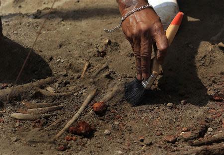 A police officer uses a brush to excavate a human skeleton at a construction site in the former war zone in Mannar, about 327 km (203 miles) from the capital Colombo, January 16, 2014. REUTERS/Dinuka Liyanawatte