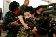 A Thai army soldier gives a weapon to a boy to pose for a picture during Children's Day celebration at a military facility in Bangkok, Thailand January 14, 2017. REUTERS/Jorge Silva