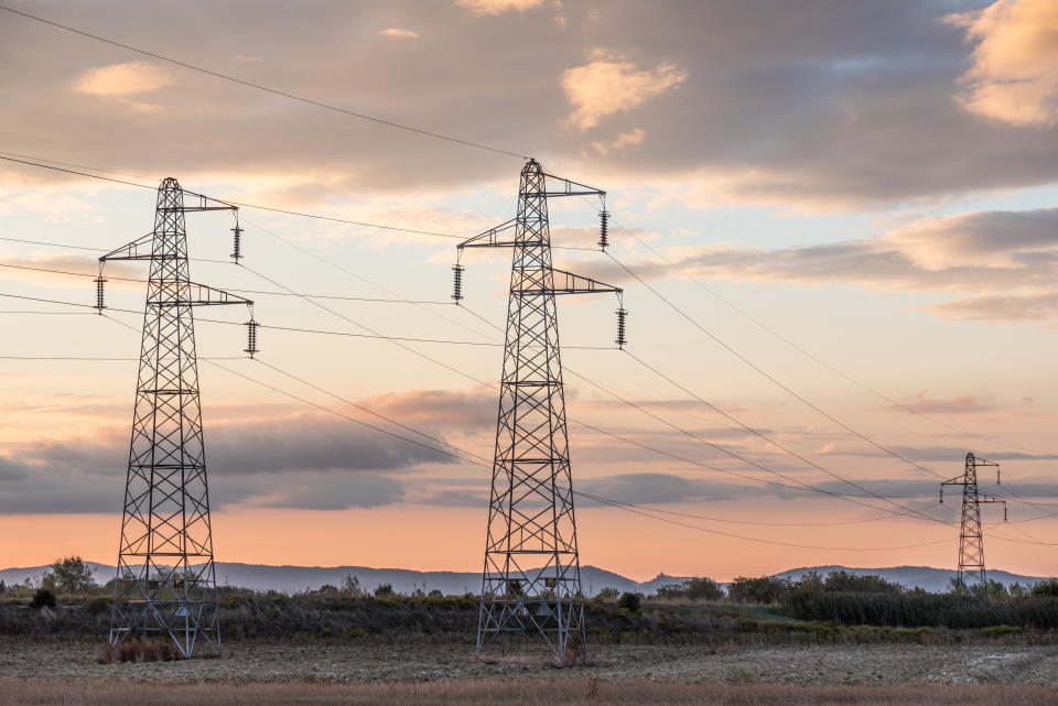 Sun setting behind a row of electricity pylons