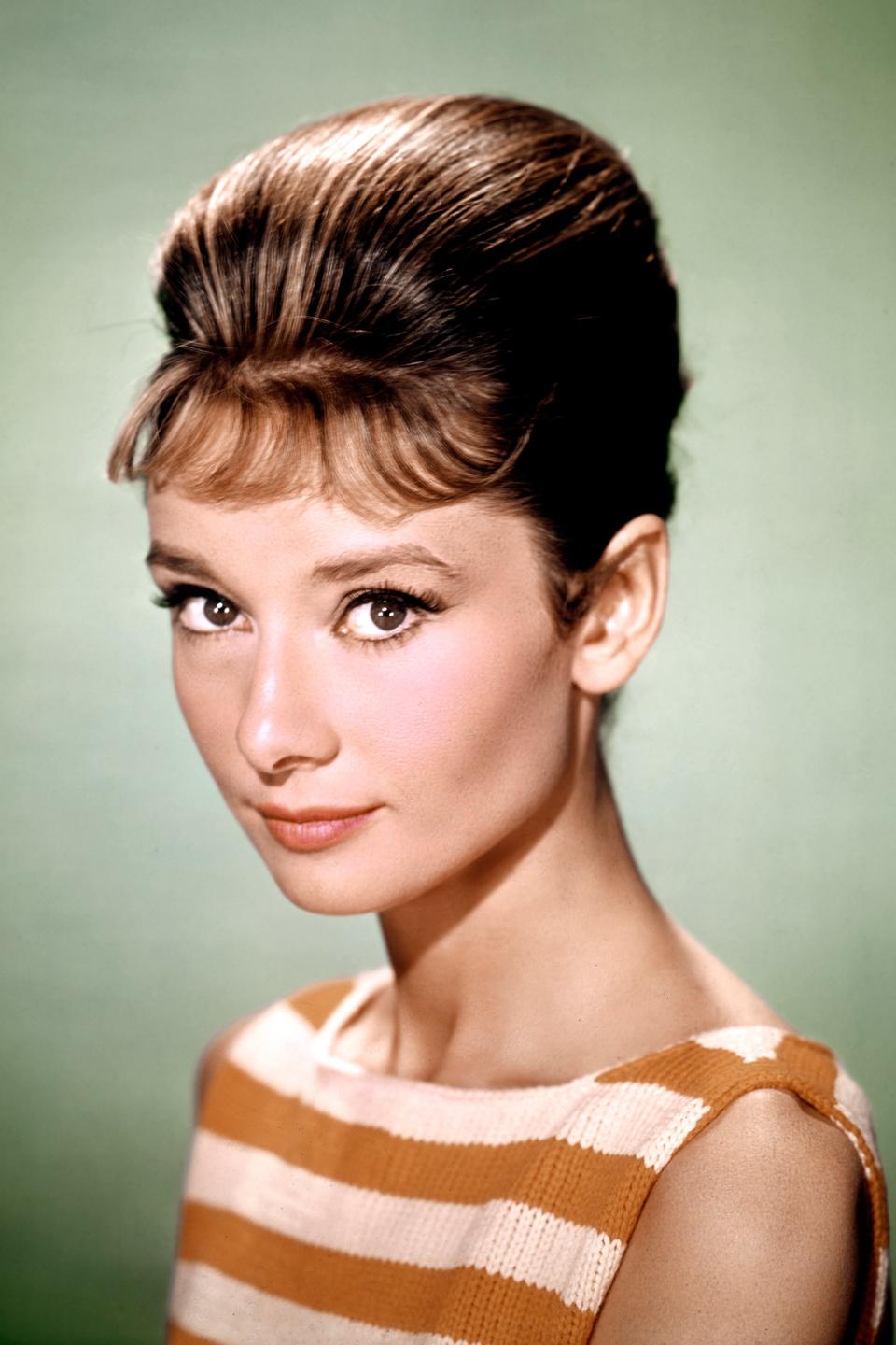 Audrey Hepburn poses in a striped sleeveless dress with her hair up