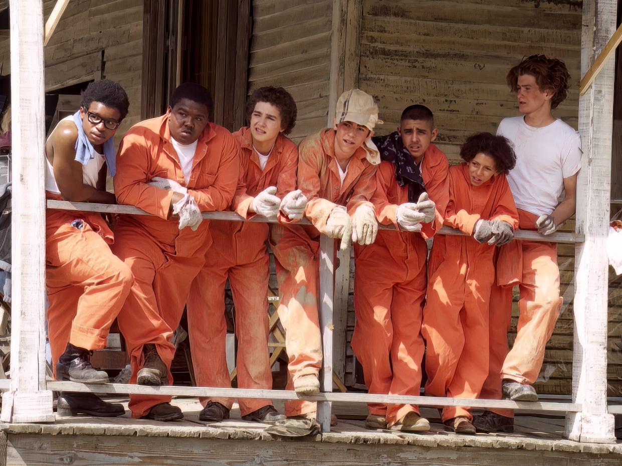 the kids filming a scene in holes in their orange jumpsuits