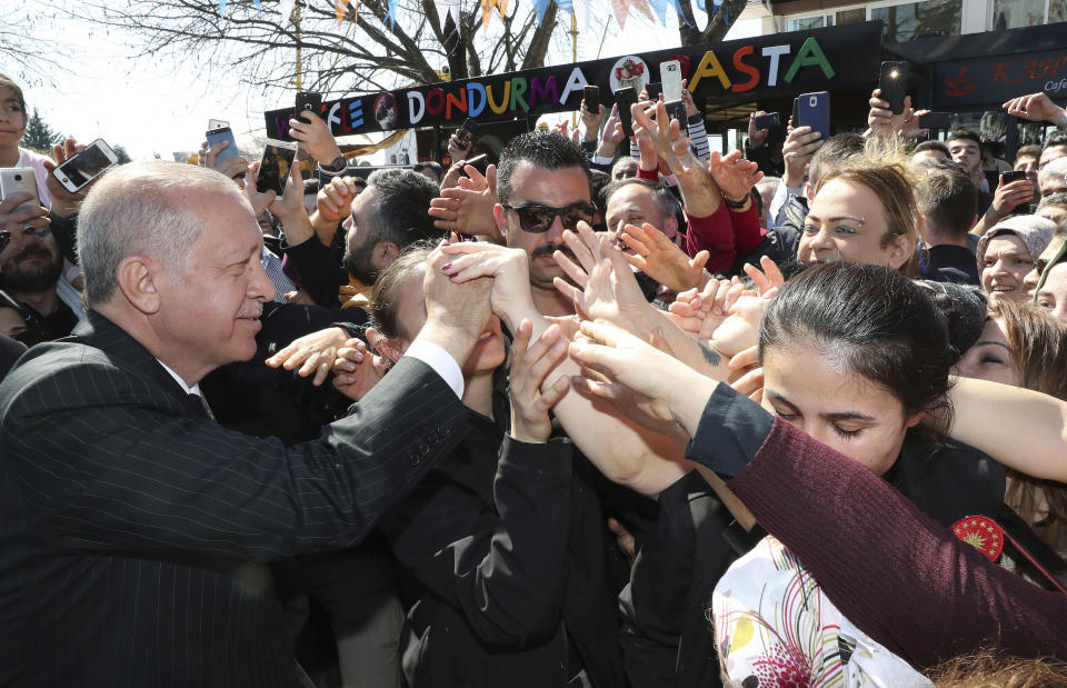 Turkey's President Recep Tayyip Erdogan shakes hands with the supporters of his ruling Justice and Development Party during a rally in Eregli, Turkey, Tuesday, March 19, 2019. Ignoring widespread criticism, Erdogan has again shown excerpts of a video taken by the attacker who killed 50 people in mosques in New Zealand at a campaign rally.(Presidential Press Service via AP, Pool)