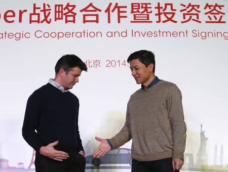 Baidu Inc. Chairman and CEO Robin Li (R) reaches out to shake hands with Uber CEO Travis Kalanick after signing their documents during the Baidu and Uber strategic cooperation and investment signing ceremony at Baidu's headquarters in Beijing December 17, 2014. REUTERS/Kim Kyung-Hoon