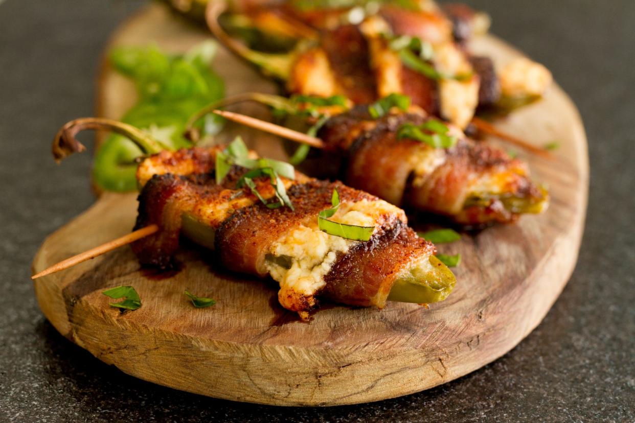 Jalapenos cut in half and stuffed with cream and shredded cheeses, wrapped in bacon secured with a toothpick, seasoned with Cajun spices, baked & garnished with fresh basil.
