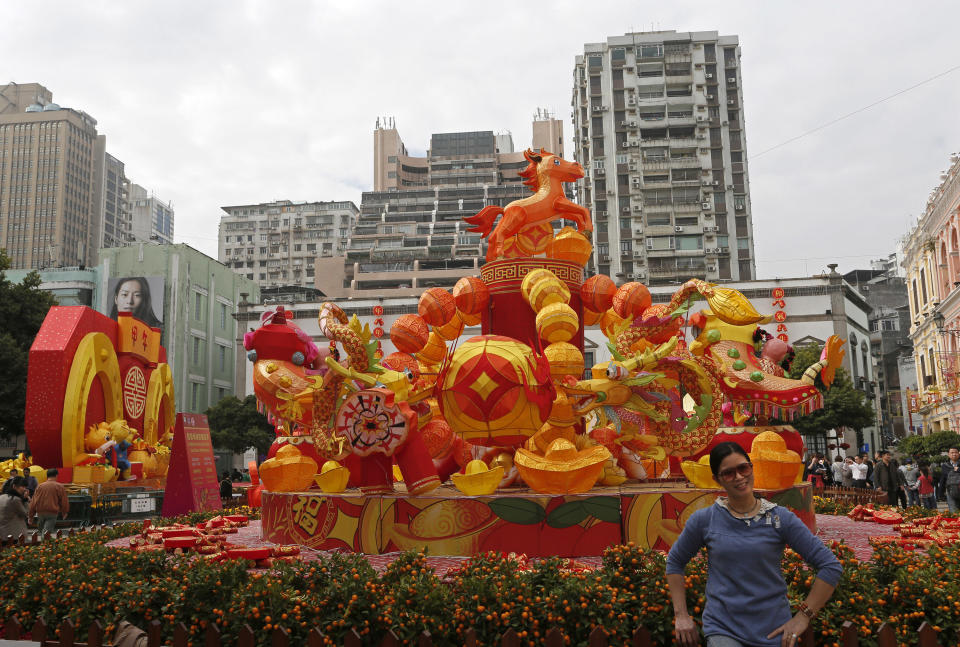 In this Feb. 1, 2014 photo, a mainland Chinese tourist poses for a picture next to decorations during a Chinese New Year celebration in Macau. The annual holiday is the busiest time of year for the former Portuguese colony, which became a special Chinese region in 1999. Many of the millions of mainland Chinese on the move during the holiday, often referred to as the world’s biggest migration, head to Macau during the festival. (AP Photo/Vincent Yu)