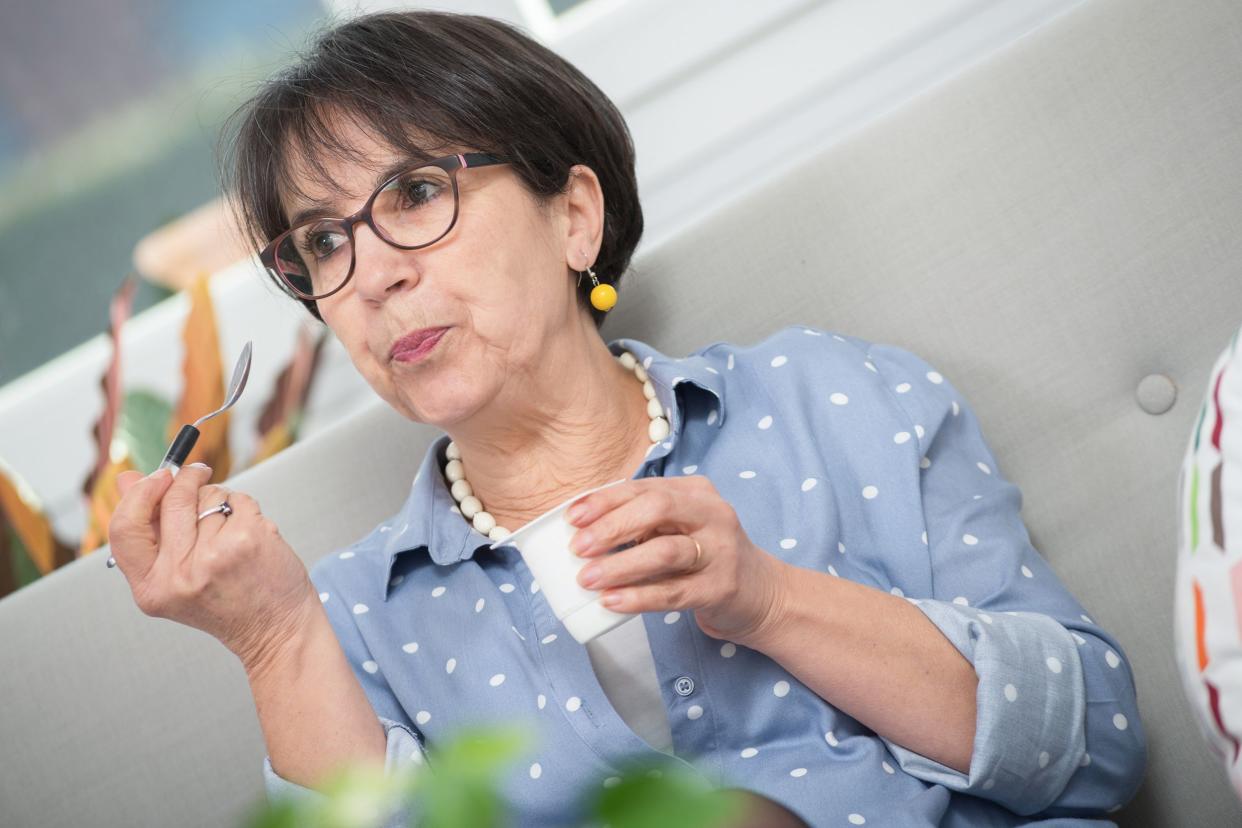 pretty mature woman eating a yogurt at home