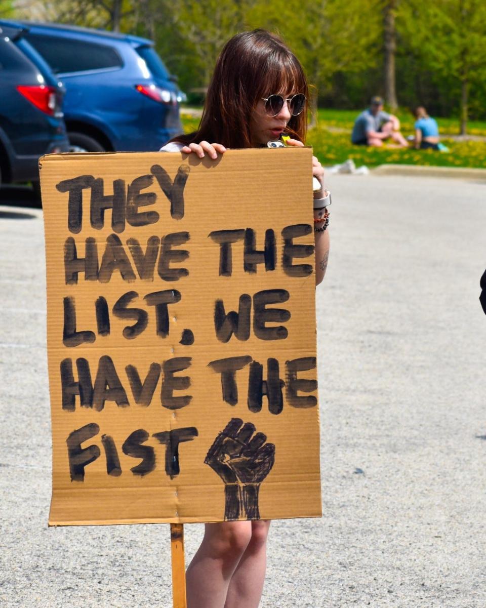 A protester in Hart Park on May 7 holds a sign that reads, "They have the list, we have the fist," speaking out against the Wauwatosa Police Department's "target list" which included the names of over 200 officials, activists, and more.