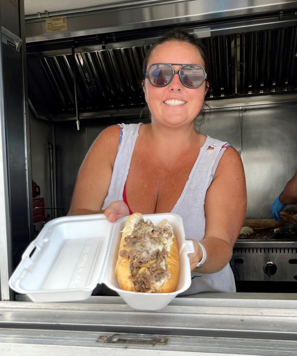 Gabby Ferraro, the owner of Double Dee's Munchies food truck, serves up one of her popular cheesesteaks.