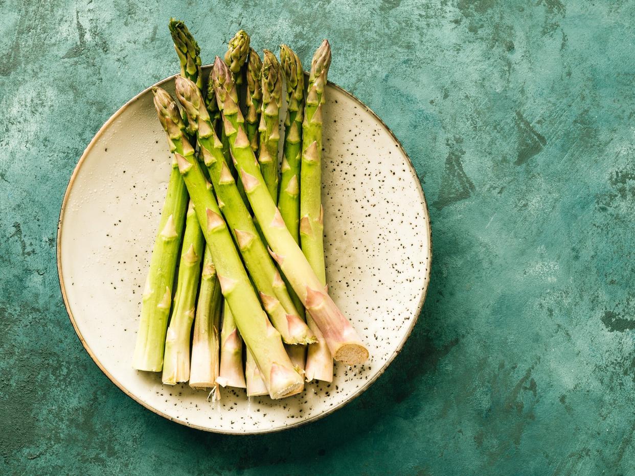overhead view of raw asparagus on a teal textured background