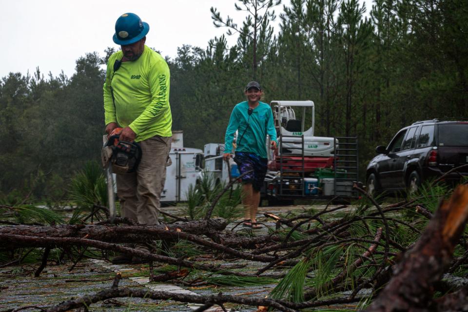 Workers for A.S.A.P. Tree and Fence clear State Road 51 of debris outside of Steinhatchee, Fla., following Hurricane Idalia's landfall in Keaton Beach Wednesday morning, Aug. 30, 2023.