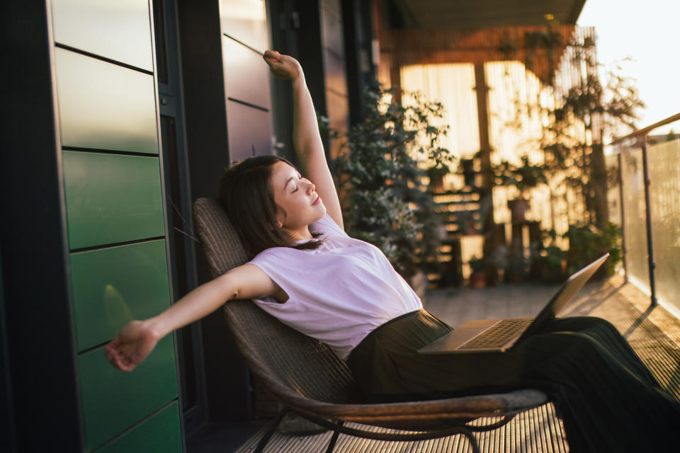 A young employee stretches while working from home